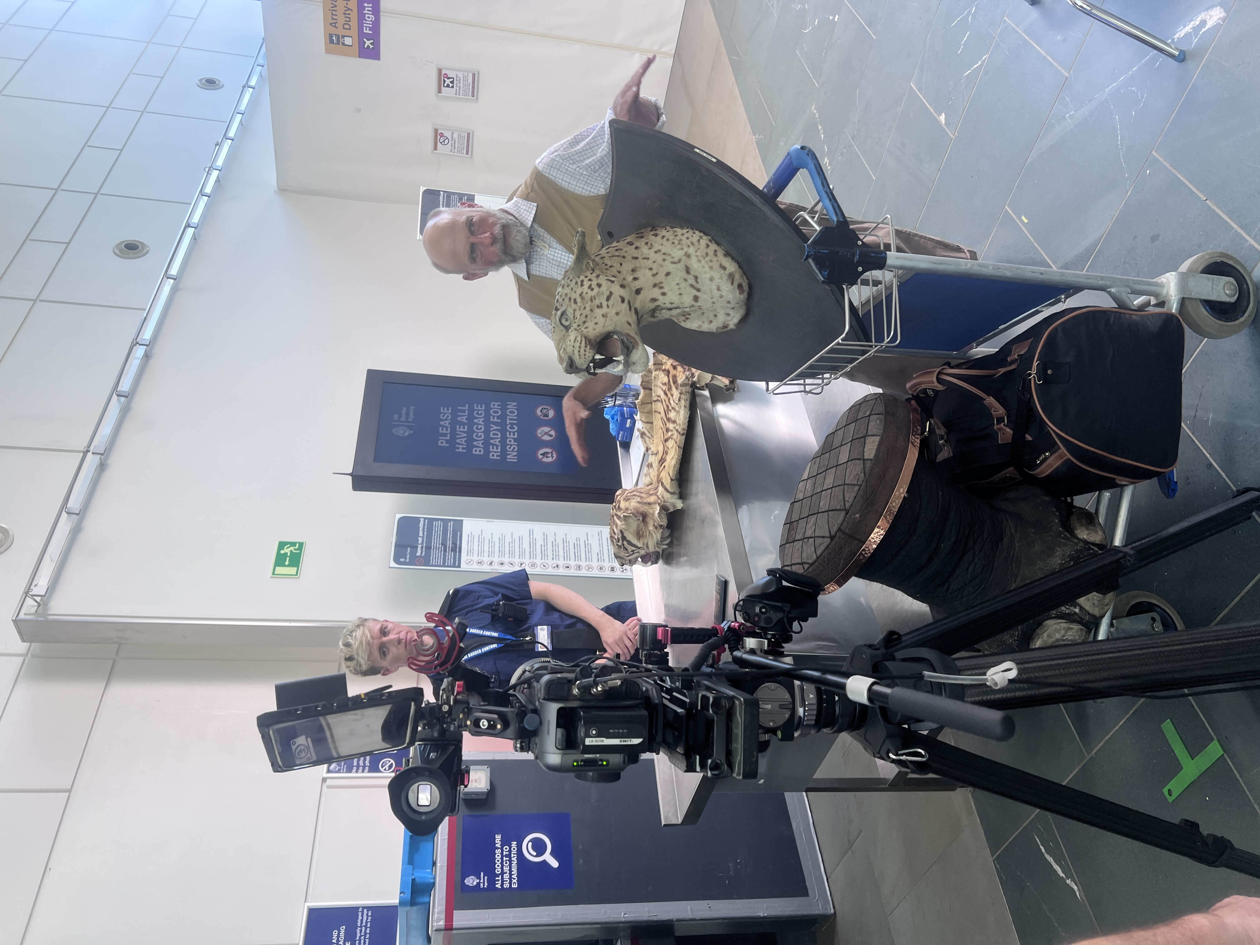 Daniel Fox as customs officer and Chris Porter as the hunter on set, with the leopard head prop – Nothing to Declare, 2026